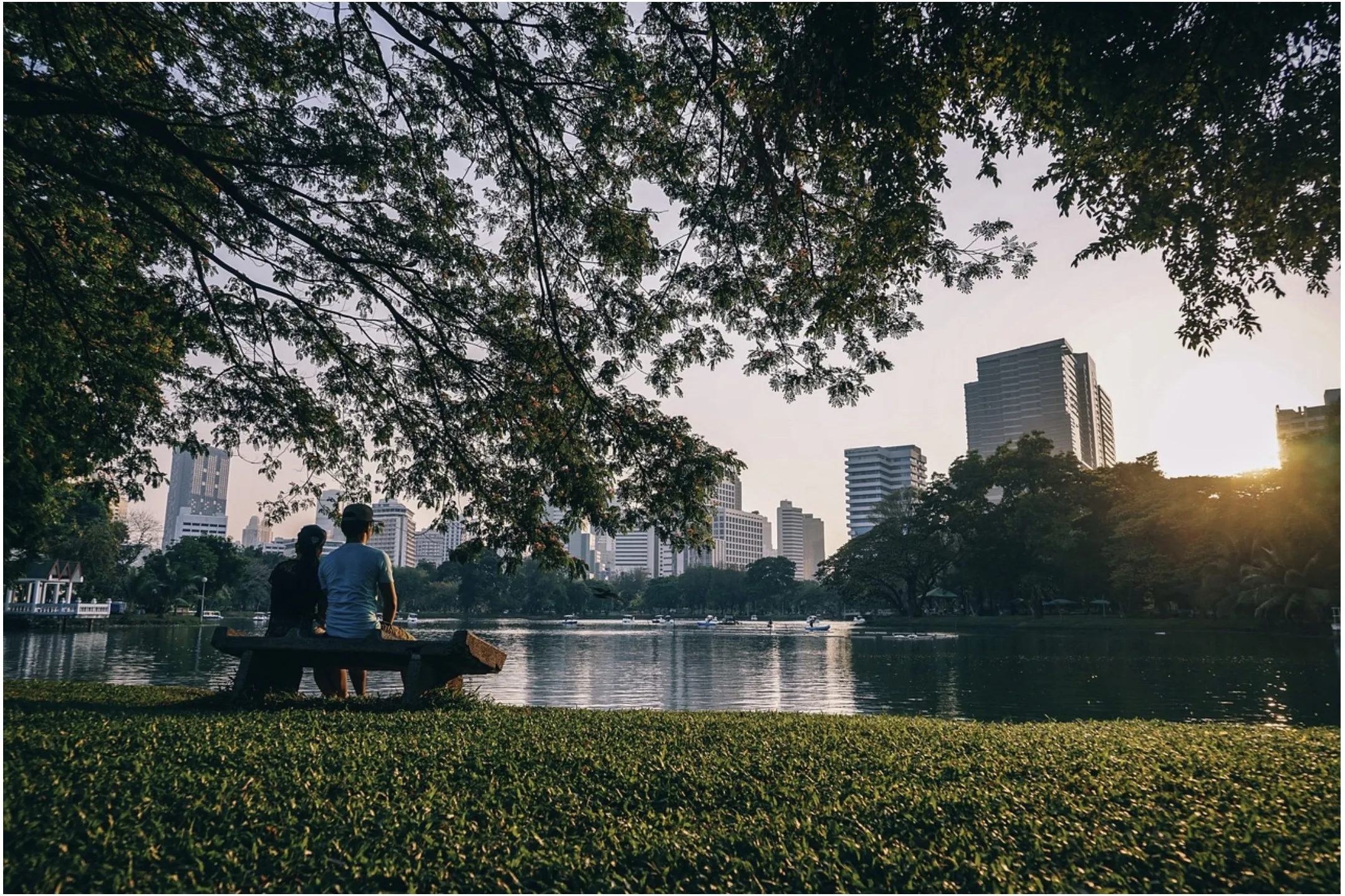 A city park at dusk with the skyline behind it